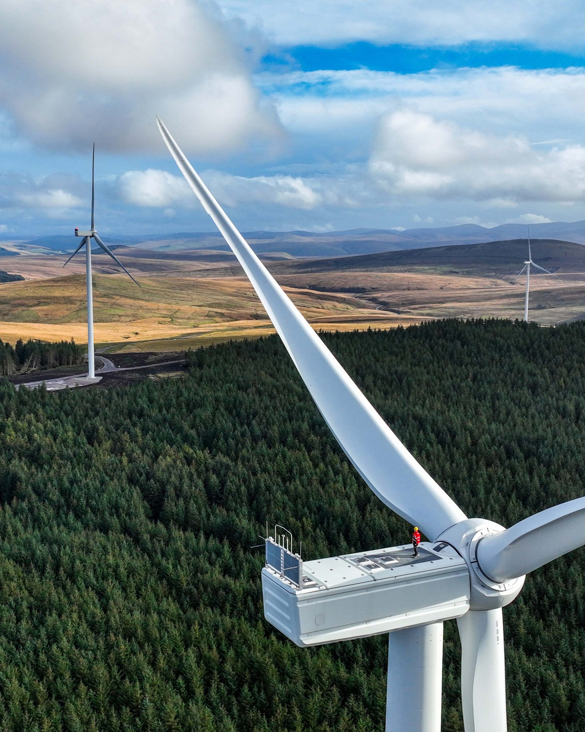Drone image of an Perigus Energy employee standing on a wind turbine